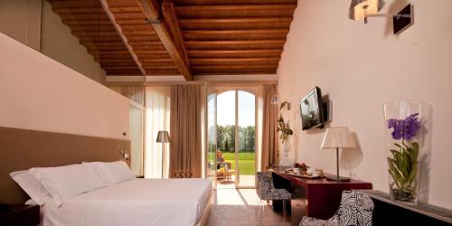 a bedroom with a bed and a desk and a window at Locanda Sant'Agata in San Giuliano Terme