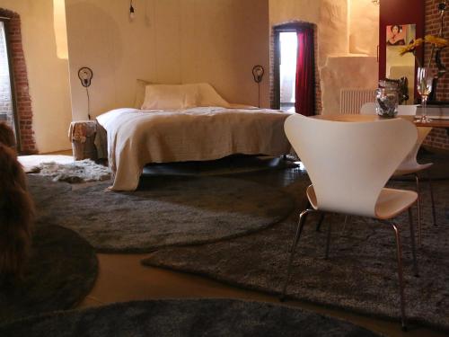 a bedroom with a bed and two white chairs at De Pelsertoren in Zwolle