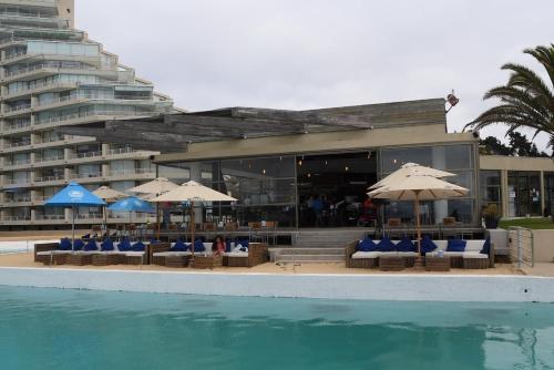 a hotel with chairs and umbrellas next to a swimming pool at Condominio San Alfonso Del Mar - Vista Inmejorable in Algarrobo
