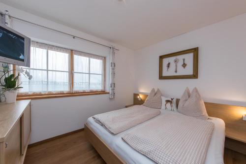 a white bedroom with a bed and a flat screen tv at Bio-Bergbauernhof Hubgut in Zell am See