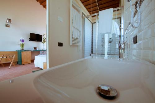 a large white tub in a room with a bedroom at Locanda Sant'Agata in San Giuliano Terme