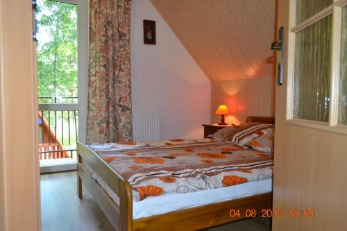 1 dormitorio con 1 cama y balcón en Dom na skraju lasu en Wilkasy