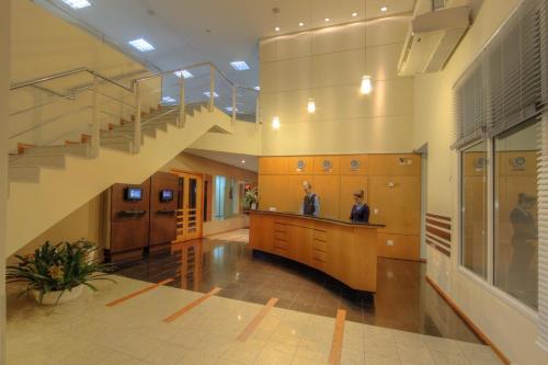 two men standing in a lobby with a staircase at Bristol Centro Civico Curitiba in Curitiba