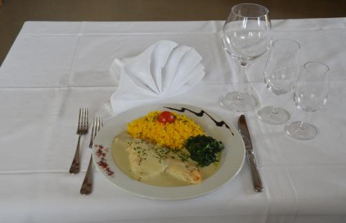 a plate of food on a white table with wine glasses at Hotel Restaurant Bahnhof in Schüpfen