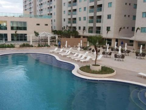 a swimming pool with chairs and a palm tree in a building at Salinas Park Resort in Salinópolis