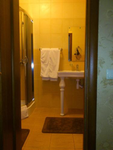 a bathroom with a sink and a shower with towels at Status Hotel in Poltava