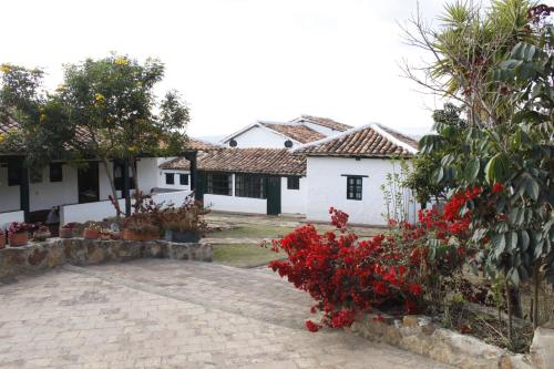 a house with red flowers in front of a yard at Posada Campestre La Casona in Villa de Leyva