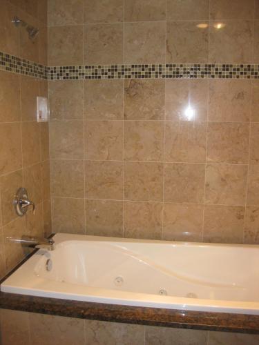 a bath tub in a bathroom with a tile wall at Acorn Motor Inn in Oak Harbor