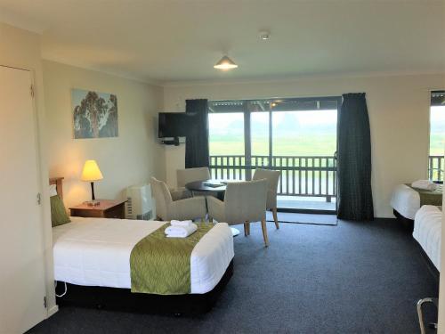 a hotel room with two beds and a balcony at Haast River Motels & Holiday Park in Haast