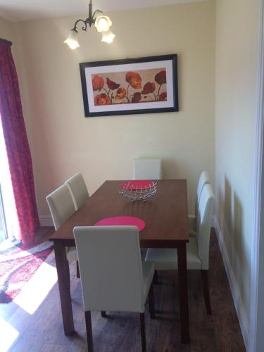 a dining room table with white chairs and a wooden table at Kilkee Bay Apartments in Kilkee