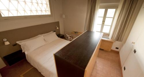 a bedroom with a bed with a desk and two windows at Locanda Sant'Agata in San Giuliano Terme