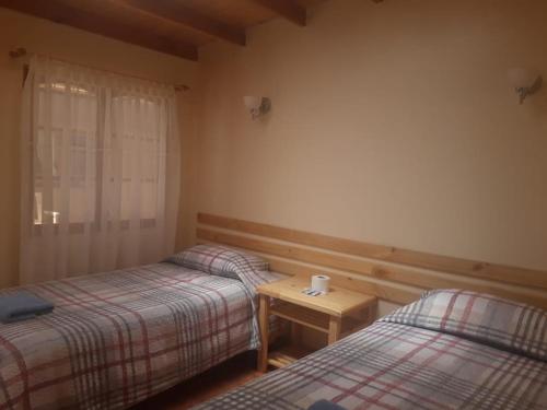 a room with two beds and a table in it at CASA MACAW in San Pedro de Atacama