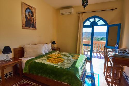 a bedroom with a bed and a balcony with a window at Maison D'hotes Sahara in Aoufous