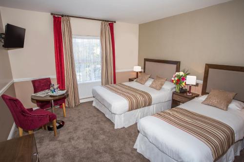 a hotel room with two beds and a window at Cahir House Hotel in Cahir