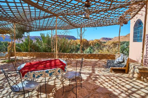 een patio met een tafel en stoelen onder een pergola bij Maison D'hotes Sahara in Aoufous