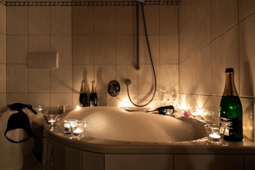 a bath tub with wine bottles and lights in a bathroom at Gämsle Hotel, Wirtshaus & mehr in Schoppernau