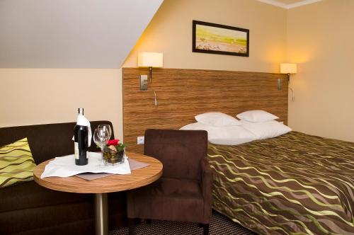 a hotel room with a bed and a table with a chair at Hotel La Siesta & Medical Spa in Jastrzębia Góra
