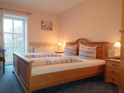 a bedroom with a wooden bed and a window at Landhotel Nonnenroth in Hungen