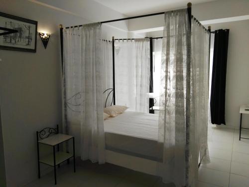 a bedroom with a canopy bed with white curtains at Residencial Casa da Luz in Mindelo