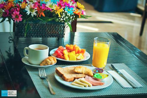 a table with two plates of food and a cup of orange juice at Tequendama Hotel Medellín - Estadio in Medellín