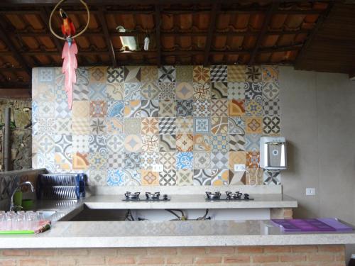 a kitchen with a counter with tiles on the wall at Pousada e Hostel Holandês in Abraão