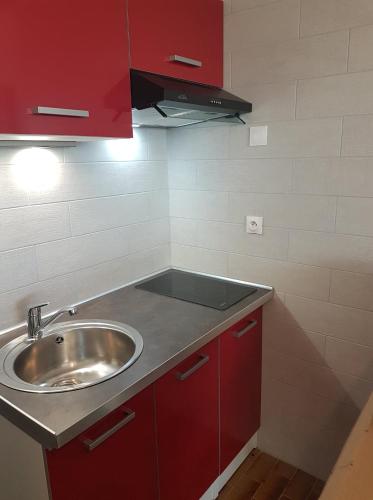 - une cuisine avec un évier et des placards rouges dans l'établissement Heliopolis F39, au Cap d'Agde