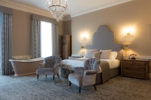 a bedroom with a bed and a tub and a chandelier at Hawkstone Hall Hotel & Gardens in Shrewsbury