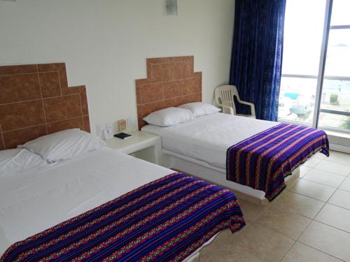 a hotel room with two beds and a window at Paraiso del Pescador in Rincon de Guayabitos
