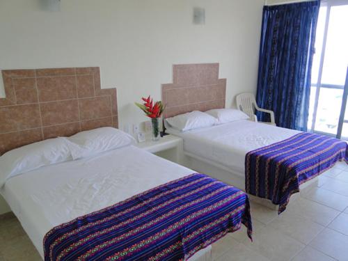 a hotel room with two beds and a window at Paraiso del Pescador in Rincon de Guayabitos