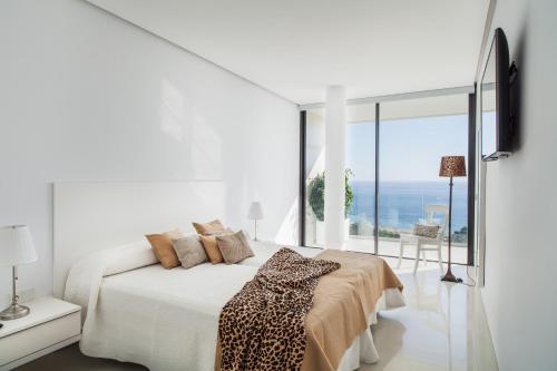 a white bedroom with a bed and a large window at Villa Alkaram de lujo con vistas panorámicas al mar in Zahara de los Atunes