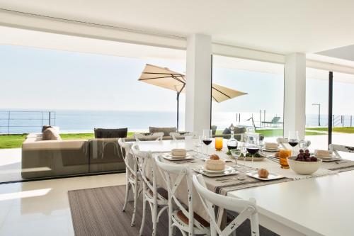 a dining room with a table and chairs and a couch at Villa Alkaram de lujo con vistas panorámicas al mar in Zahara de los Atunes