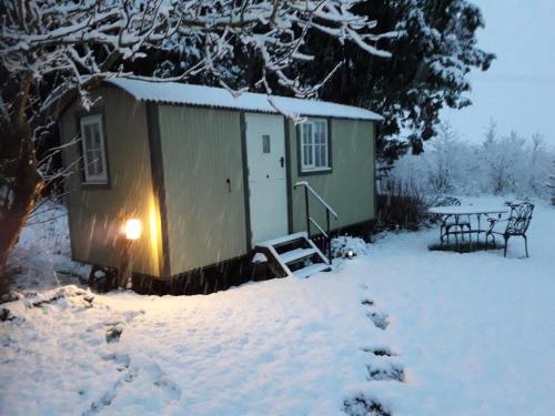 a small shed with a table in the snow at Abbey Farm Glamping & Cottage in Thame