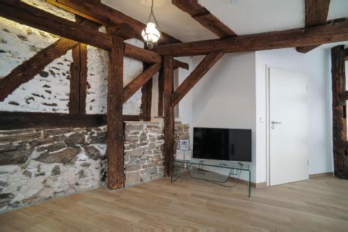 a living room with a stone wall and a flat screen tv at Designpension Traumschloss Hotel Garni in Wernigerode