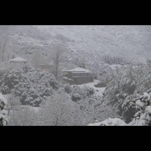 a snow covered yard with a house and trees at Villa Agno - Βίλα Αγνώ in Ãno KariaÃ­