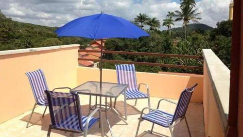 a table and chairs with a blue umbrella on a balcony at Suites Solar dos Arcanjos Guaramiranga in Guaramiranga