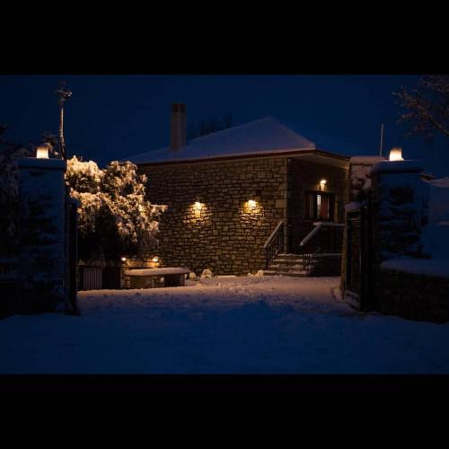 a brick house with lights in the snow at night at Villa Agno - Βίλα Αγνώ in Ãno KariaÃ­