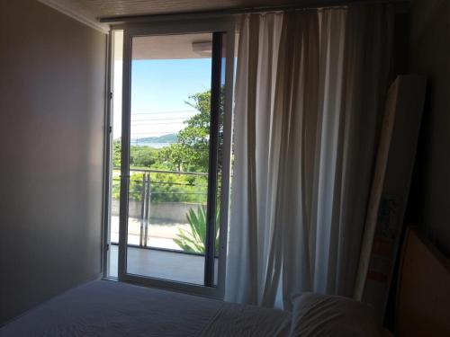 1 dormitorio con ventana y vistas a un balcón en Praia da Pinheira, alto padrão, 5 dormitórios, 4 BWC, climatizada 150 m praia, en Palhoça