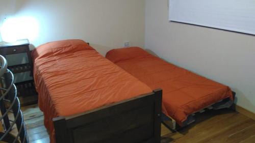 2 Betten in einem Schlafzimmer mit orangefarbener Bettwäsche in der Unterkunft Cabaña El Tordillo in Potrero de Garay