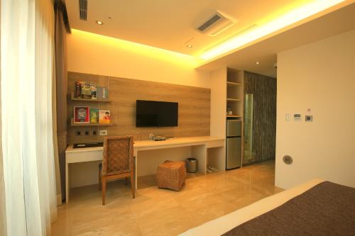 a bedroom with a desk with a television on a wall at Darlon Hotel in Hsinchu City