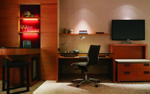 a room with a desk with a chair and a television at Kerry Hotel Pudong, Shanghai - Indoor Connecting to Shanghai New International Expo Centre in Shanghai