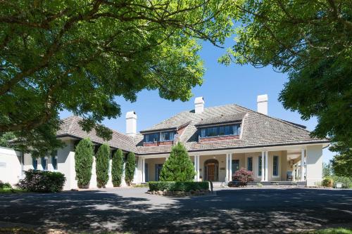 a house with a driveway and trees at Peppers Manor House in Sutton Forest