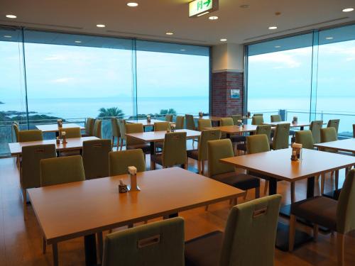 a restaurant with tables and chairs and large windows at THE HOTEL YAKUSHIMA ocean & forest in Yakushima