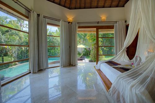 a bedroom with a bed in a room with windows at Mayana Villas in Canggu