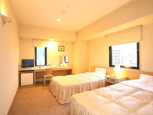 Habitación de hotel con 2 camas y escritorio con ordenador en Hotel Pearl City Tendo, en Tendō