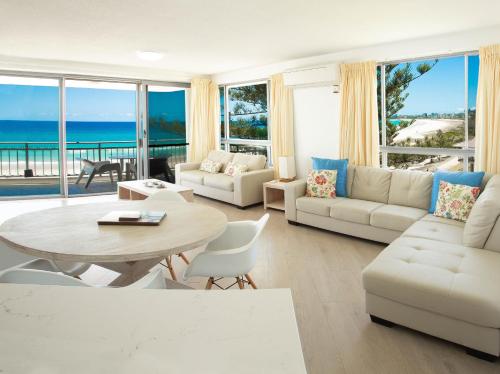 una sala de estar con mesa y sillas y el océano en Oceanside Resort - Absolute Beachfront Apartments, en Gold Coast