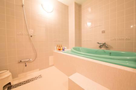 a bathroom with a tub and a toilet and a sink at Aloha Inn Aine (Adult Only) in Fukuchiyama