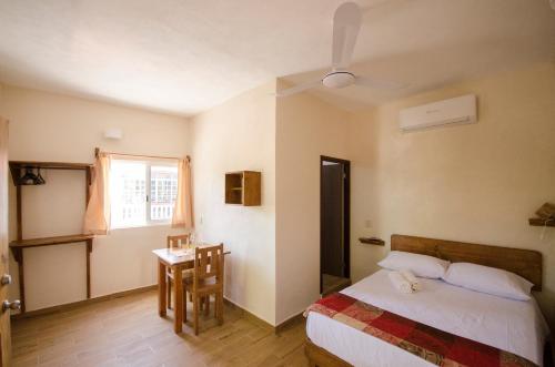 a bedroom with a bed and a table and a window at Casa Almendro in Tulum
