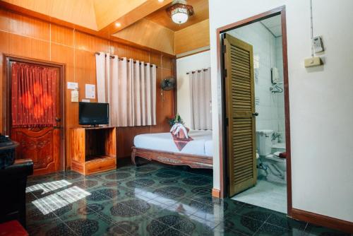 a bedroom with a bed and a tv and a bathroom at Noble Night Guesthouse in Kanchanaburi