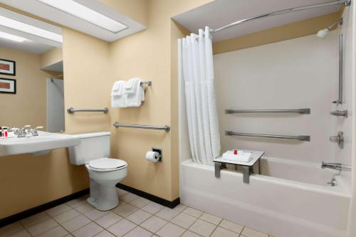 a bathroom with a toilet and a tub and a sink at Baymont by Wyndham Rocky Mount in Rocky Mount