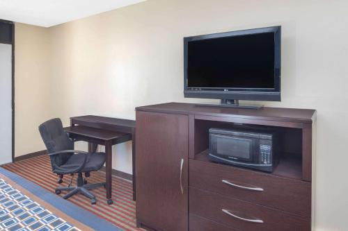 a room with a desk and a television and a chair at Travelodge by Wyndham Savannah Area/Richmond Hill in Richmond Hill
